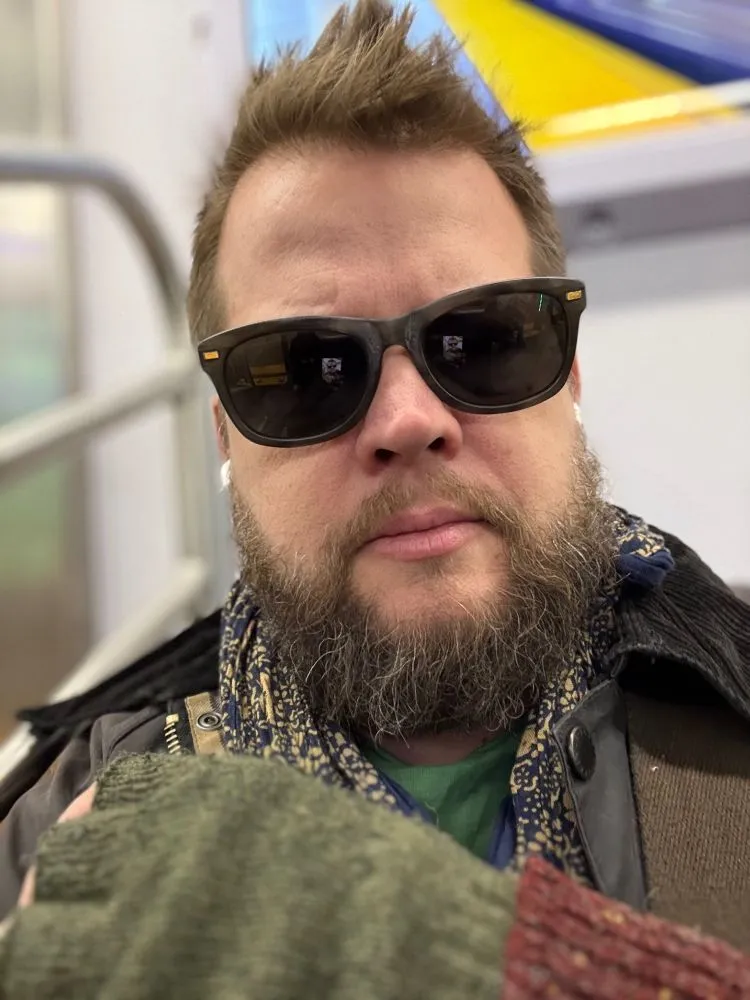 John Paul Davis wearing sunglasses and gloves on the subway